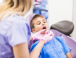 dental hygienist cleaning teeth of young boy